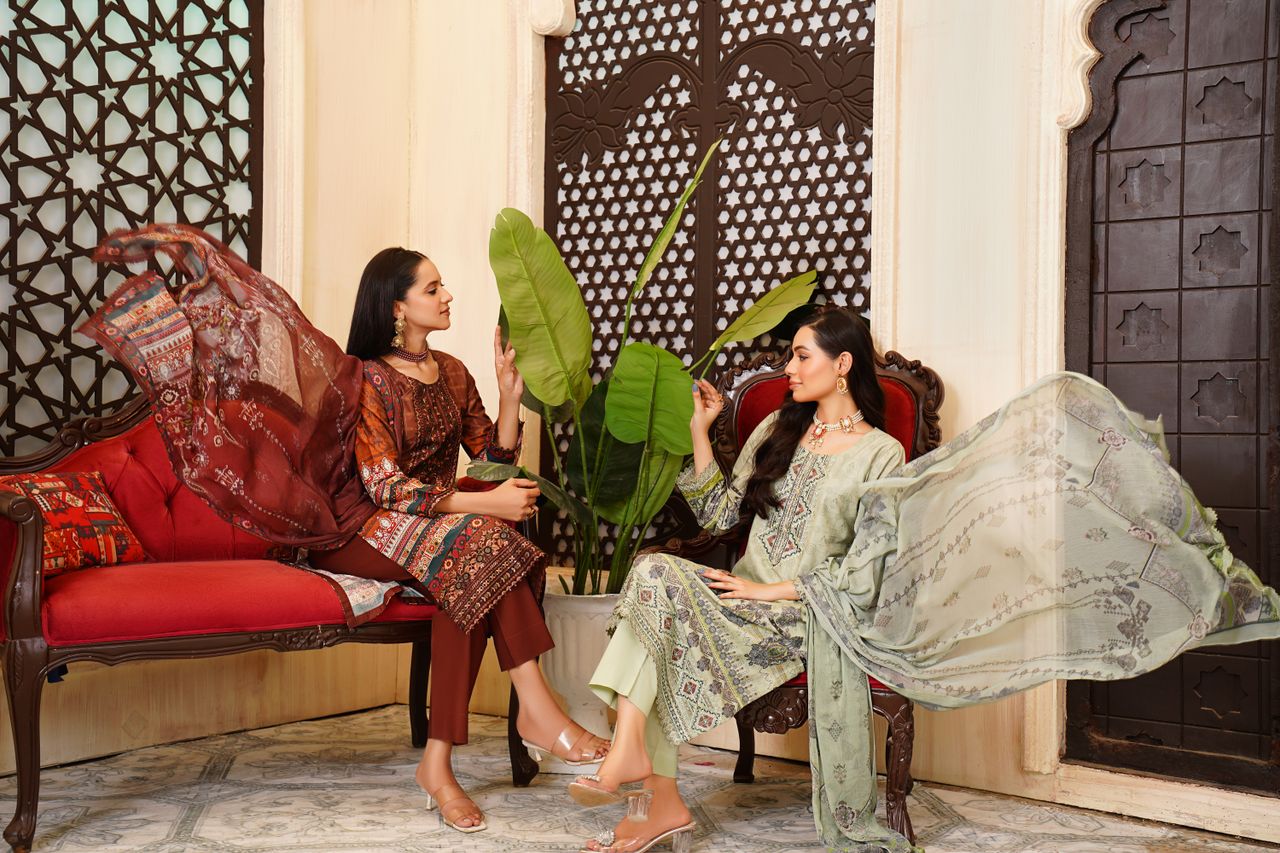 Two women in traditional Pakistani dresses posing elegantly indoors in Lahore.