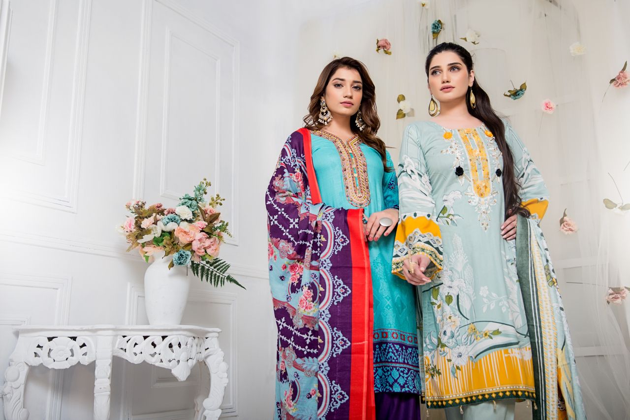 Two women in traditional clothing pose elegantly in an indoor setting with floral decor.